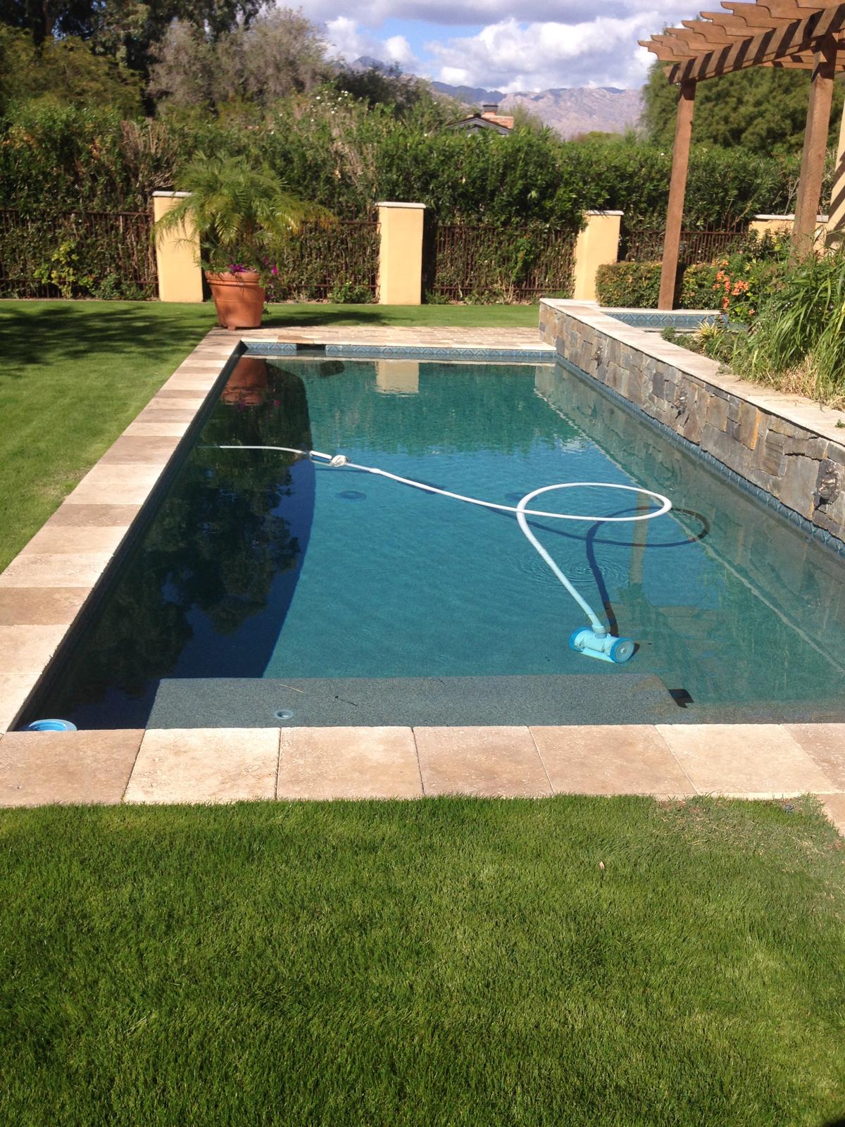 Rectangular pool with travertine coping and artificial grass surround in Arizona