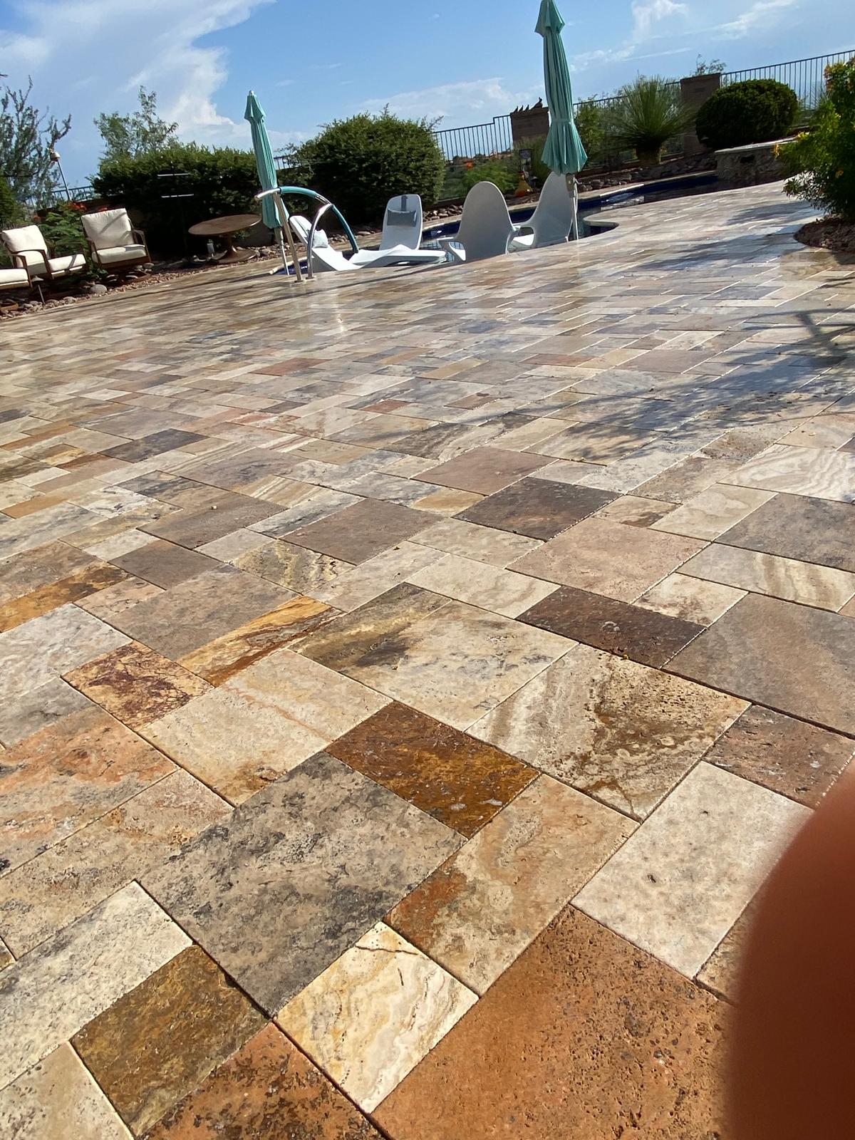 Sealed travertine pool deck pavers with umbrellas and white lounge chairs in Arizona