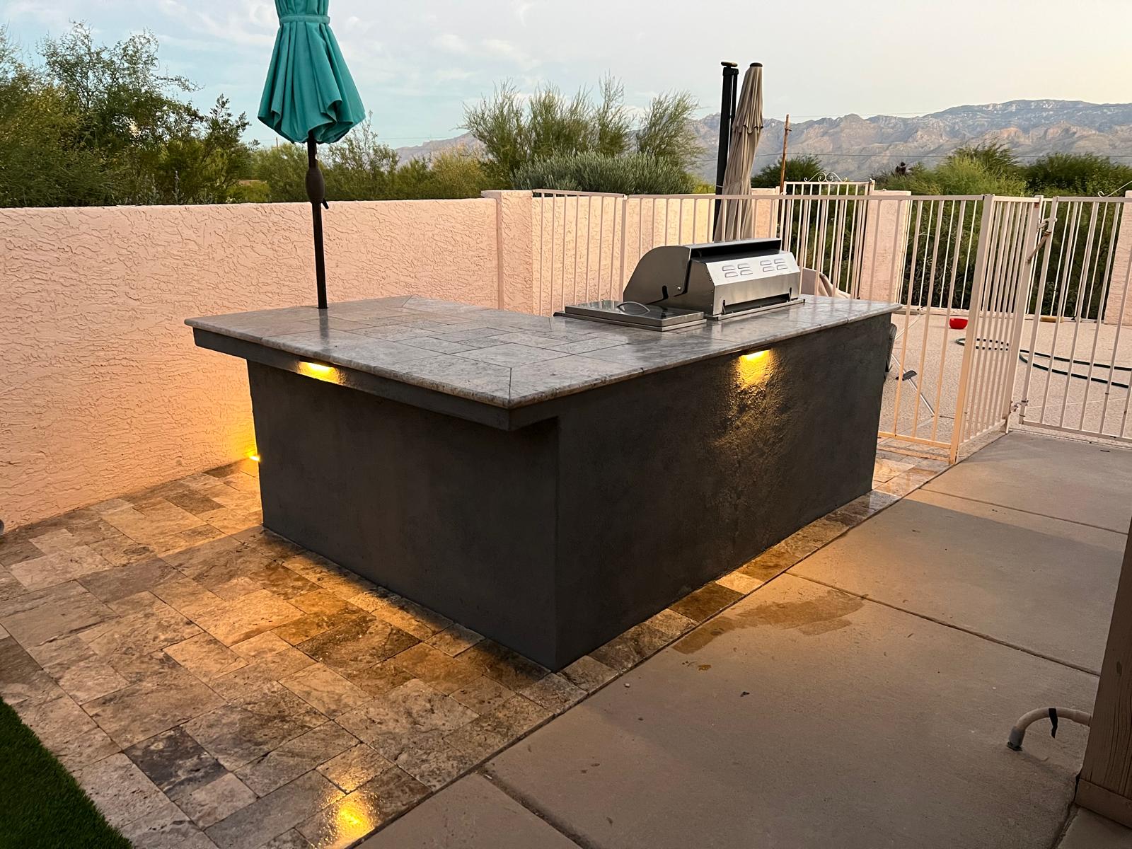 Illuminated freestanding outdoor BBQ island with mountain views in an Arizona backyard