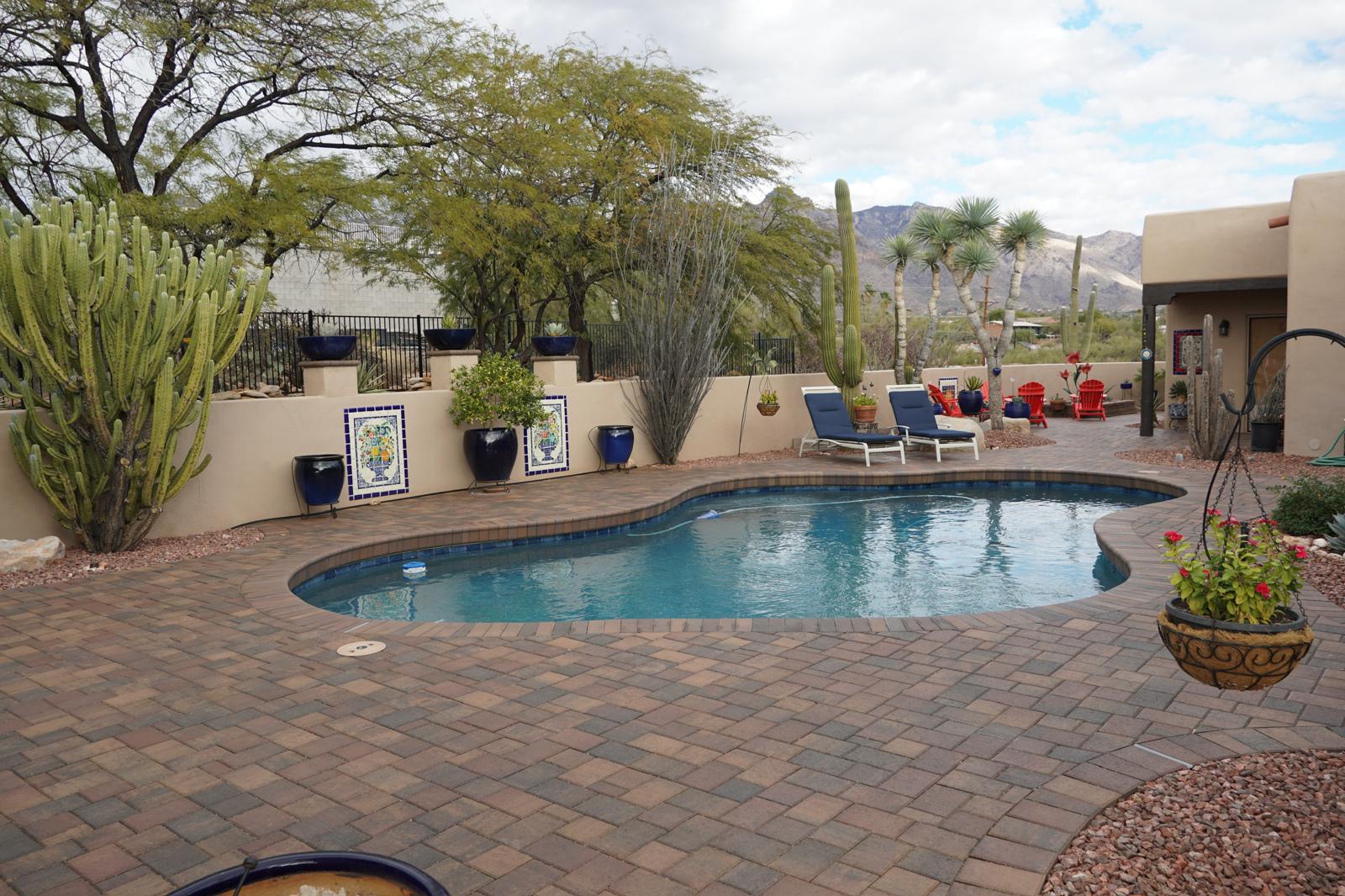 Curved paver pool deck with desert landscaping and mountain views at an Arizona home