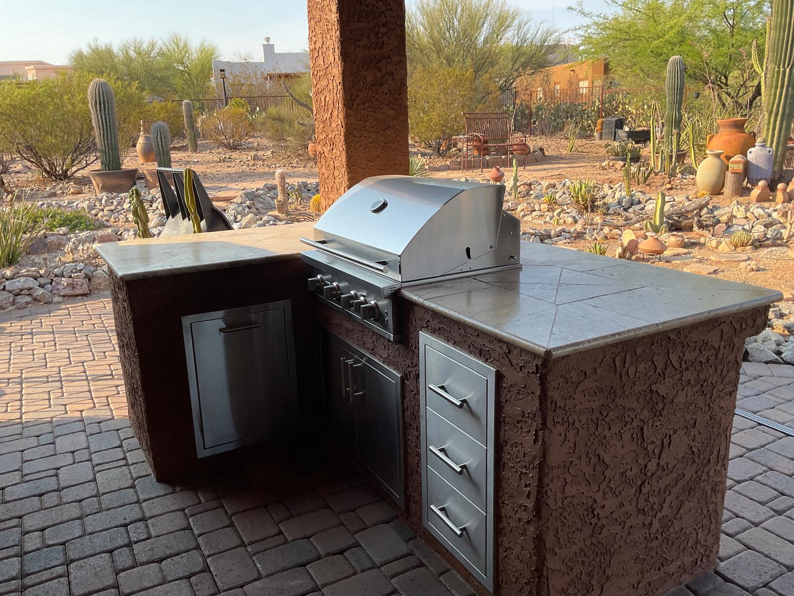 Custom stucco outdoor BBQ island with stainless steel grill and storage in an Arizona backyard