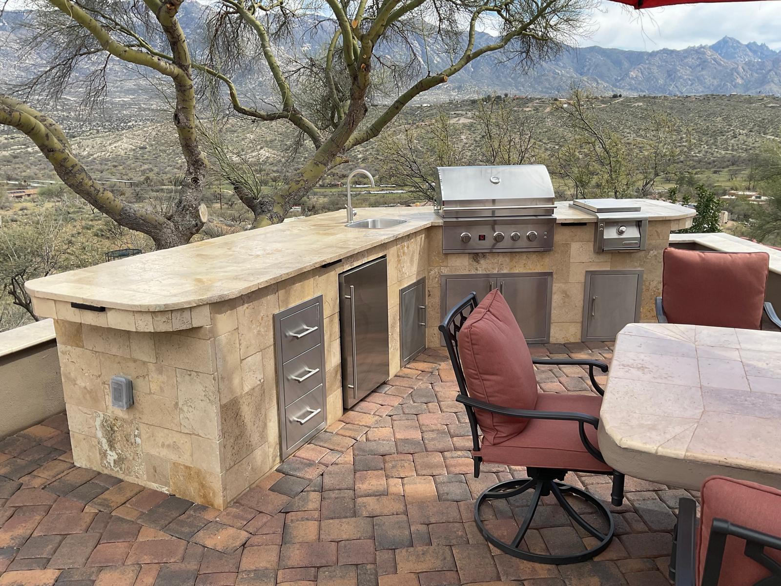 Curved stone outdoor kitchen with grill, sink and mountain views in an Arizona backyard