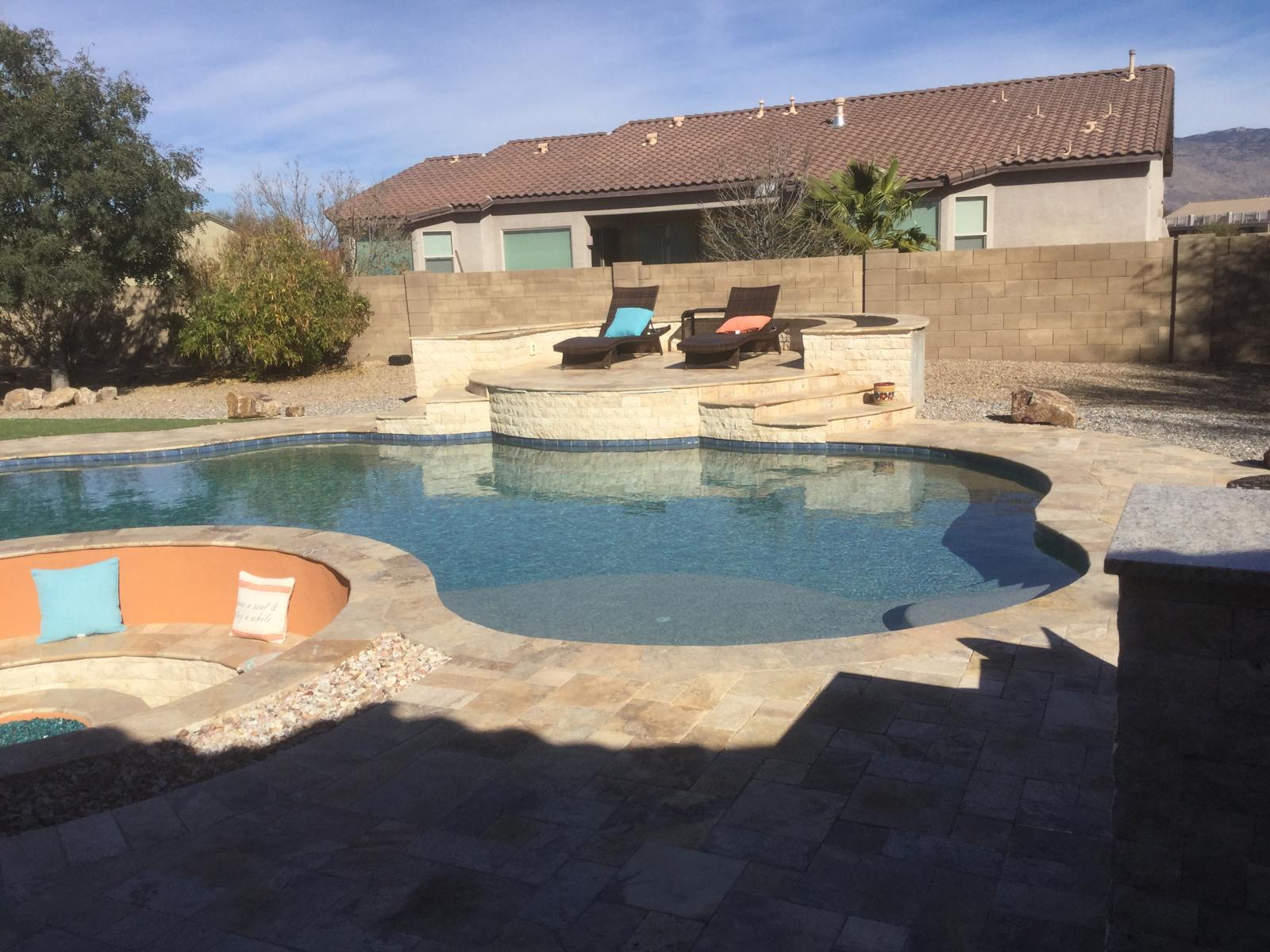 Pool with raised travertine spa, lounge chairs and paver deck in Arizona
