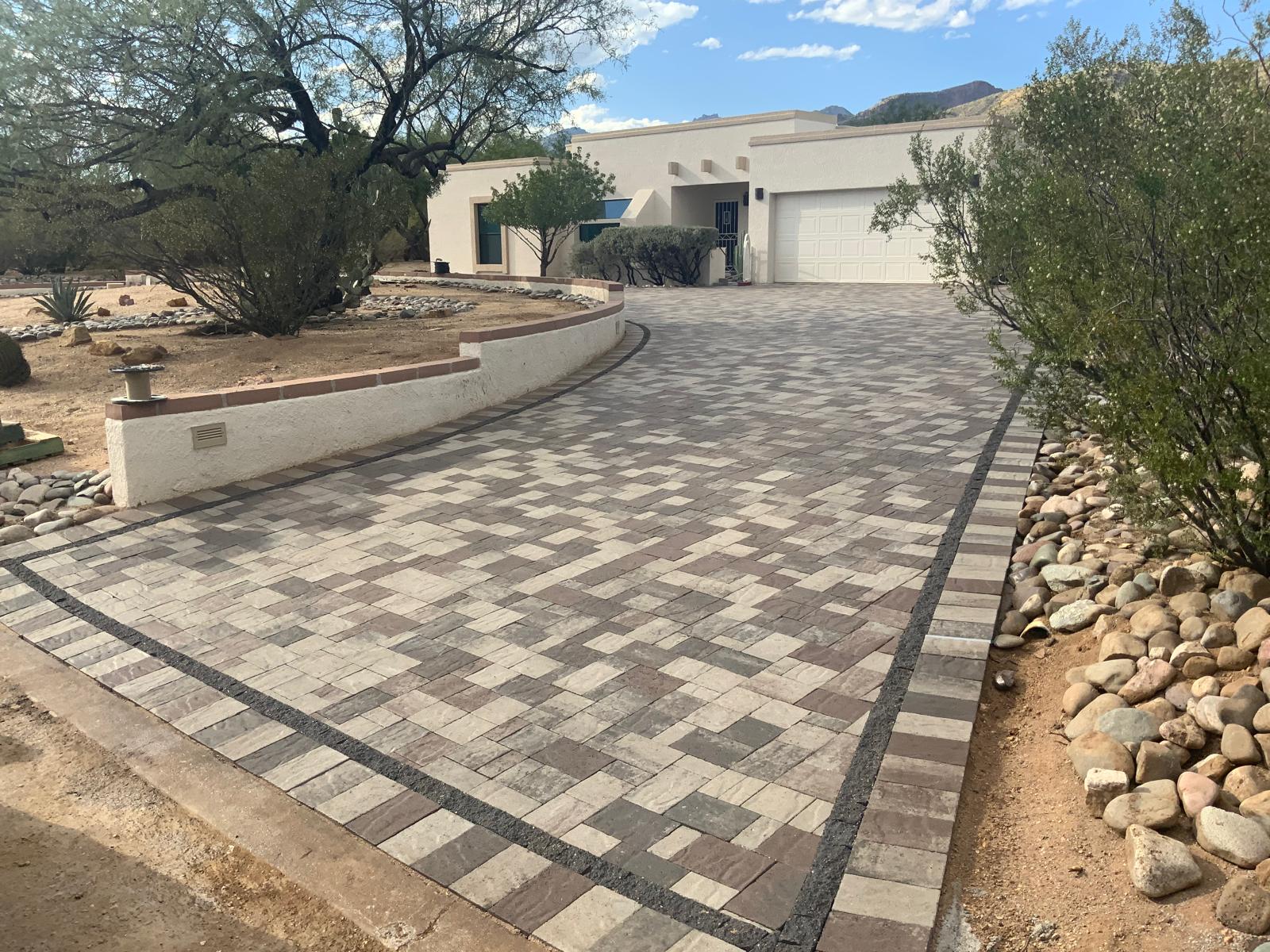 Curved paver driveway with contrasting border and low retaining wall in Phoenix Arizona