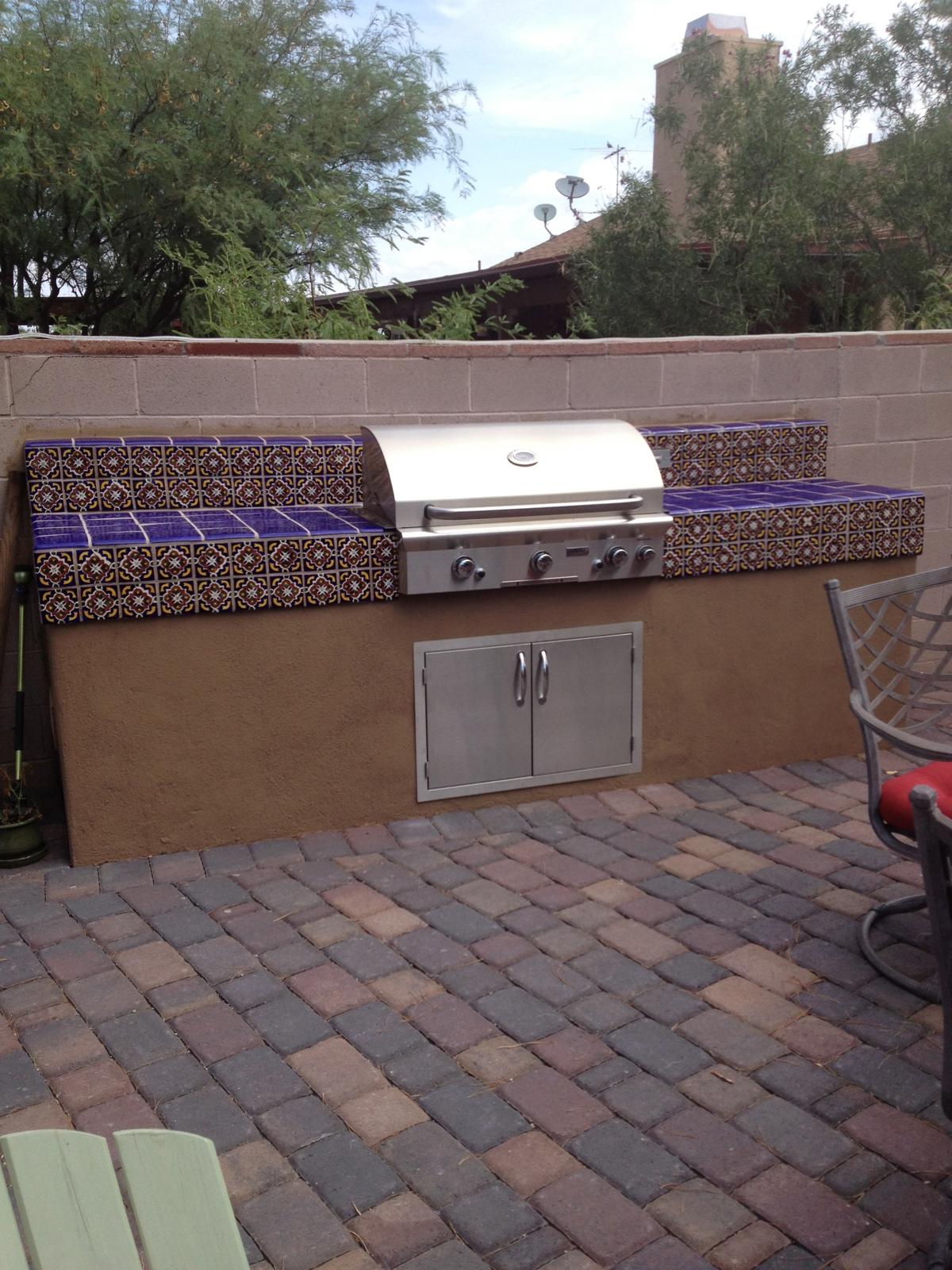 Built-in barbecue grill with decorative tile counters on a brick paver patio in Arizona