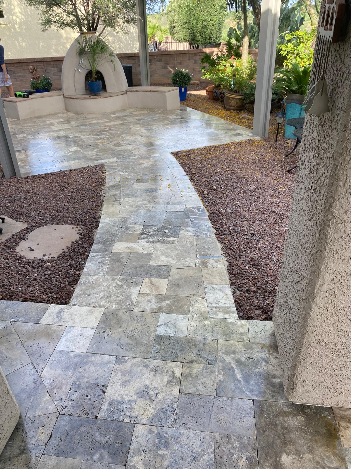 Sealed travertine patio walkway leading to an outdoor fireplace in an Arizona backyard