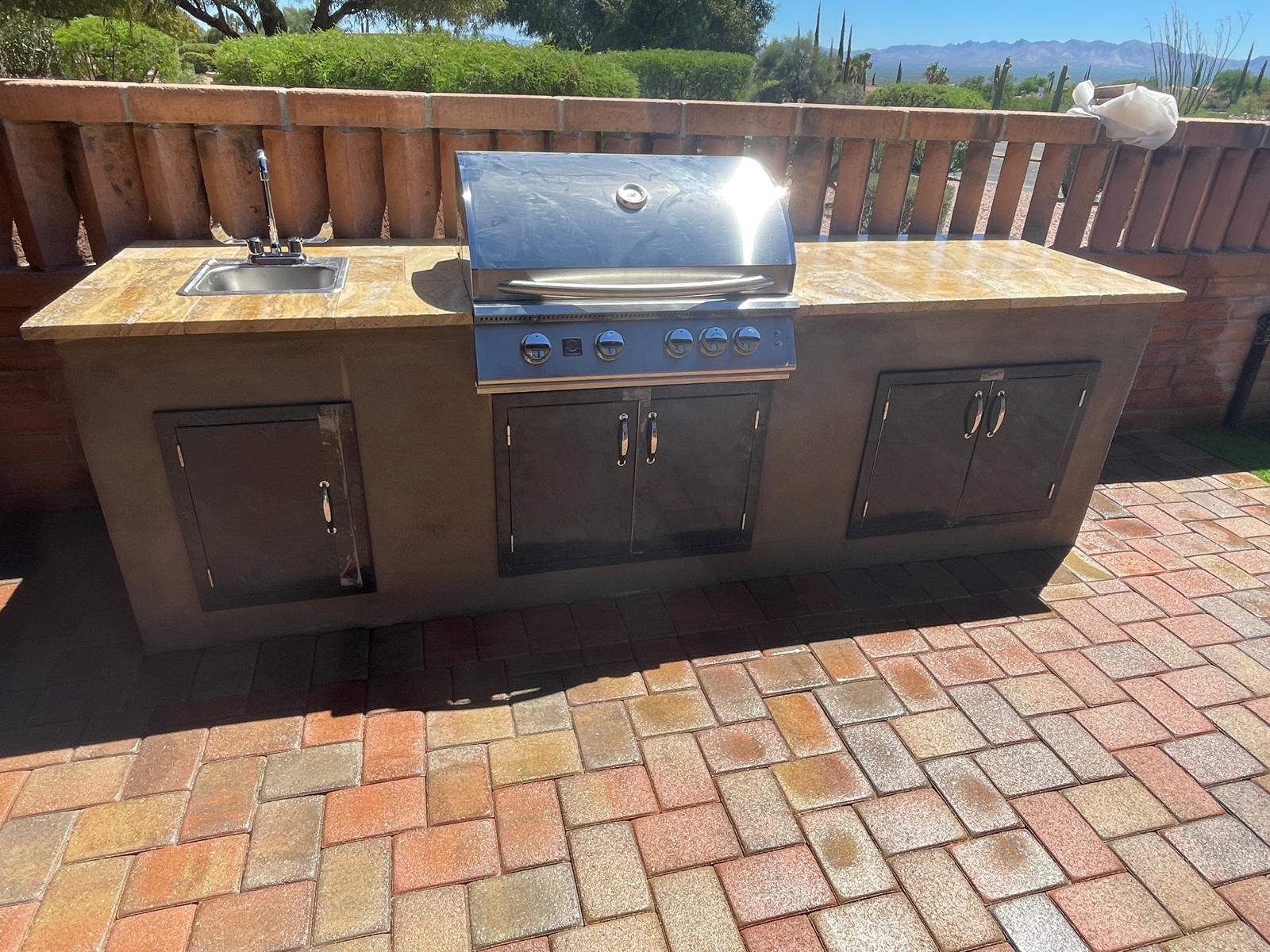 Straight outdoor BBQ island with grill, sink and storage on a brick paver patio in Arizona